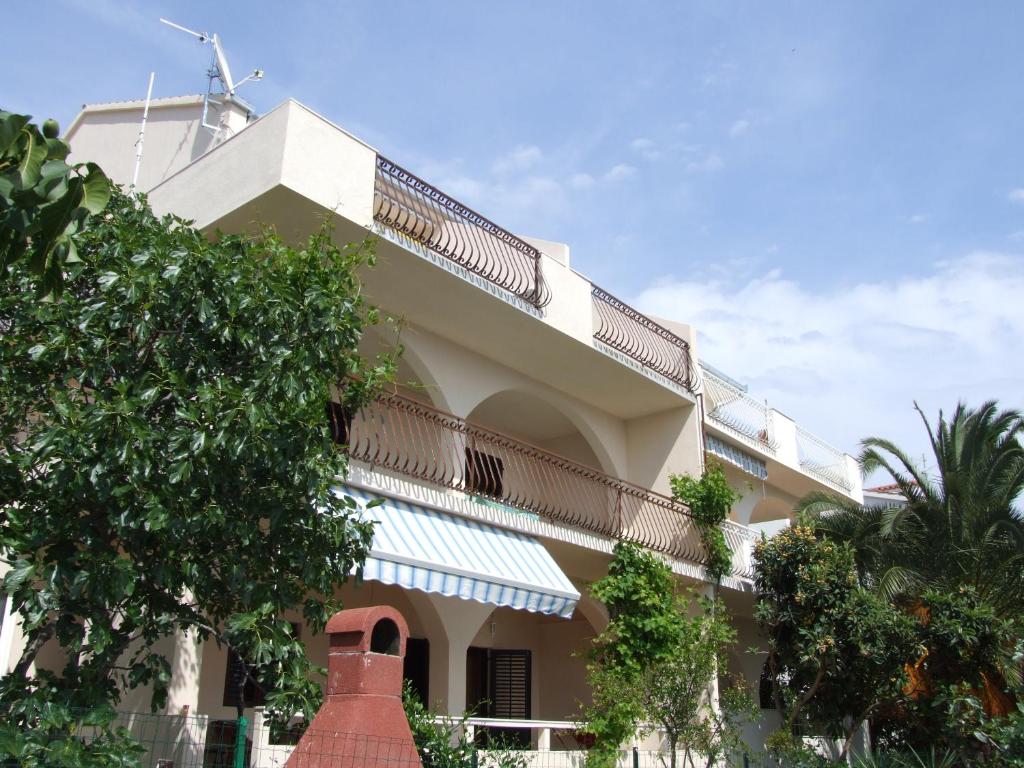 un gran edificio con balcón y un árbol en Maiden Apartments, en Trogir