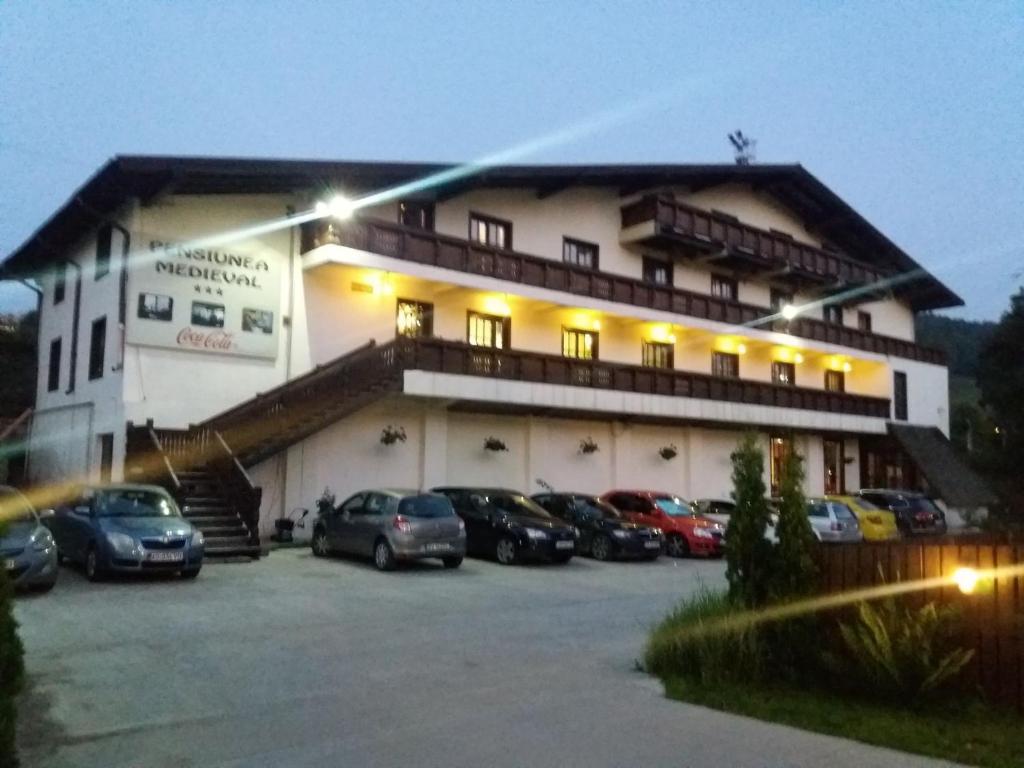 a large building with cars parked in a parking lot at Pensiunea Medieval in Predeal