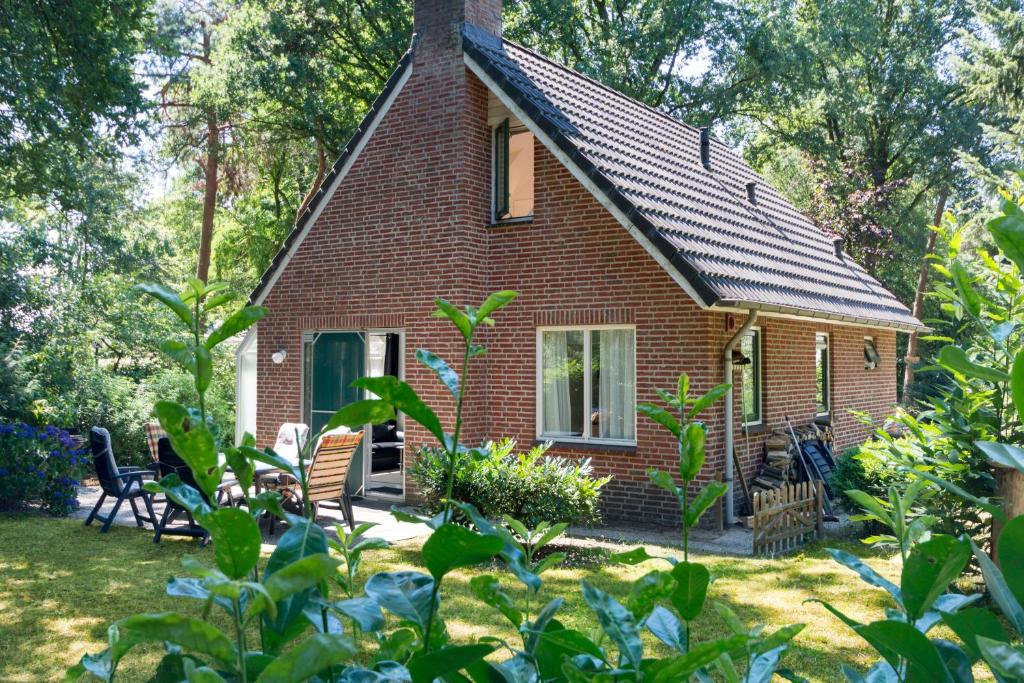 een klein rood bakstenen huis met stoelen in de tuin bij Vosseveen 62 in Zelhem