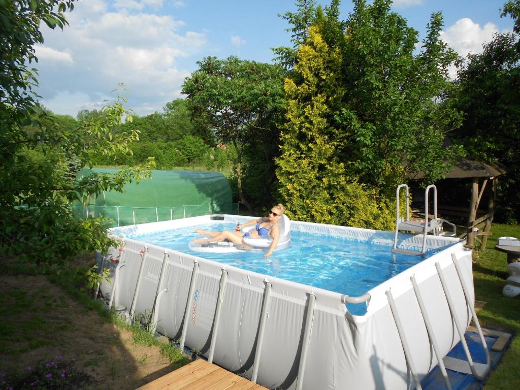 a woman in a swimming pool in a yard at Domek na Wzgórzu in Ryn