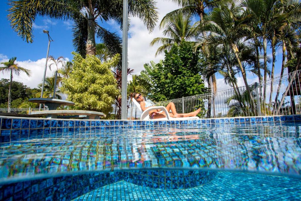 una mujer sentada en una silla junto a una piscina en BIG4 Townsville Gateway Holiday Park en Townsville