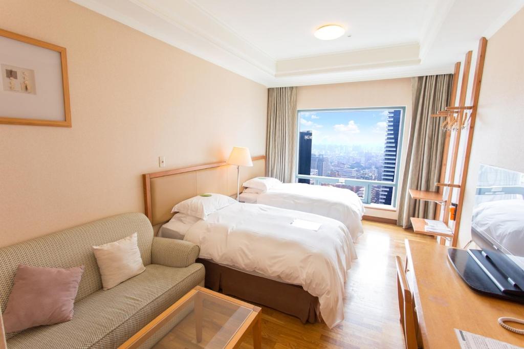 um quarto de hotel com duas camas e um sofá em Park Lane Inn em Taichung