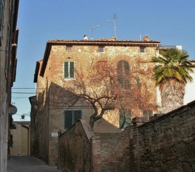 een oud bakstenen gebouw met een palmboom ervoor bij Casa Di Castello in Castelmuzio