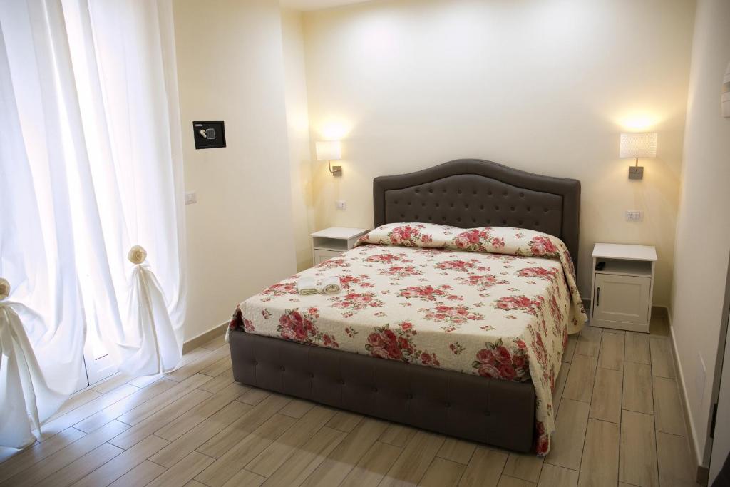 a bedroom with a bed with a floral bedspread at Ludovica Home in Giardini Naxos