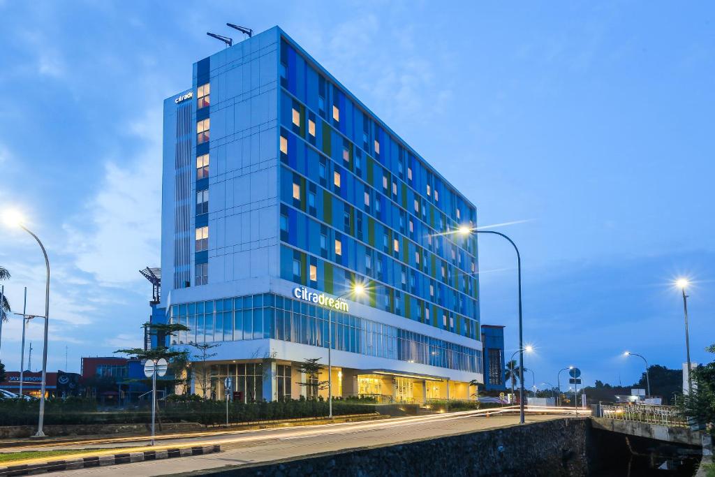 a blue building with lights on in a city at Hotel Citradream Bintaro in Serpong