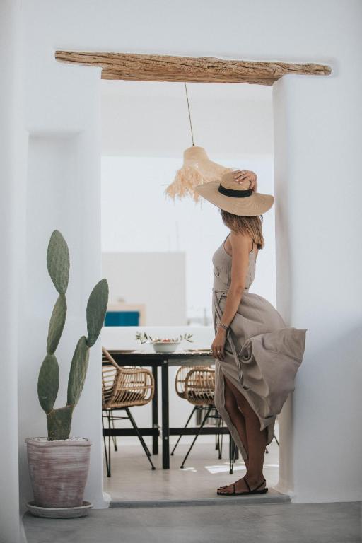 a woman wearing a hat standing next to a table at HORA SUITES in Naxos Chora