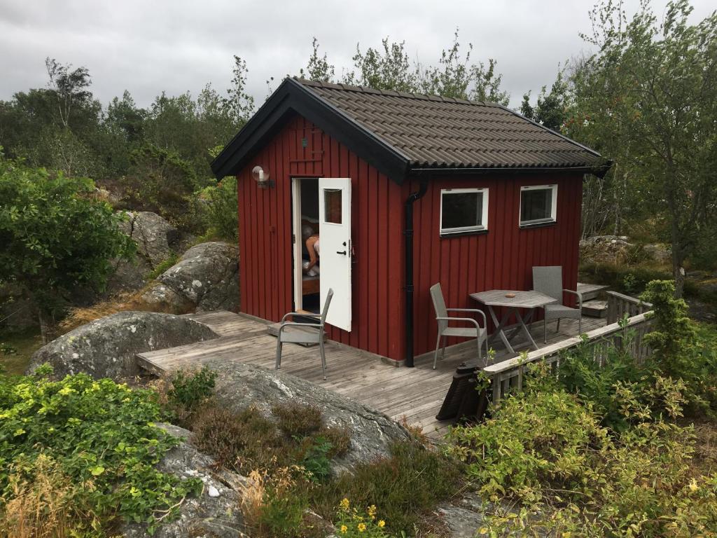 una casita roja pequeña con terraza y mesa en Marstrand, en Marstrand