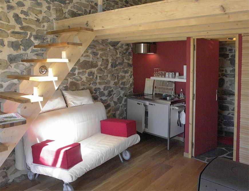 a living room with a white couch and a stone wall at Le Fritz in Queyrières