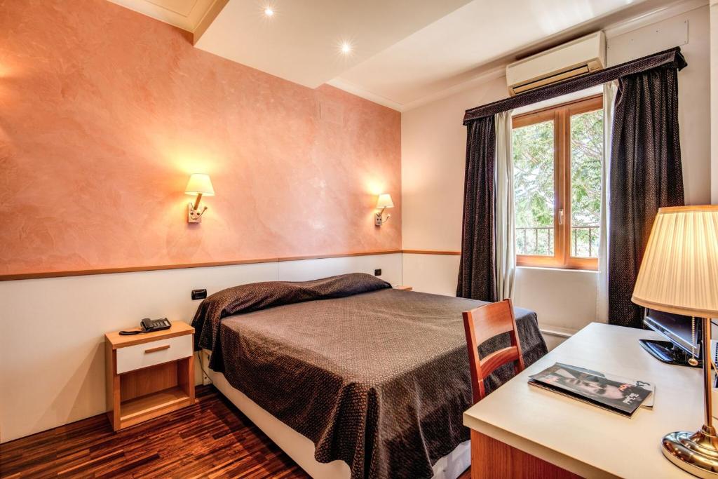 a hotel room with a bed and a desk and a window at Hotel Roma Tiburtina Metro in Rome