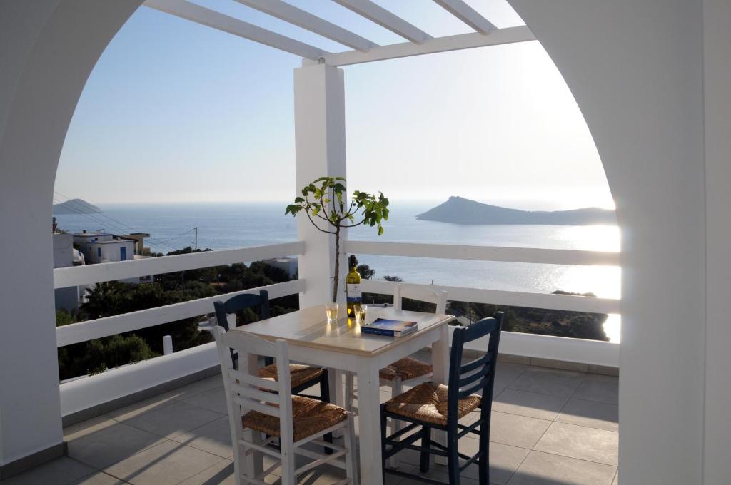 een witte tafel en stoelen op een balkon met uitzicht op de oceaan bij climbers village in Kalymnos