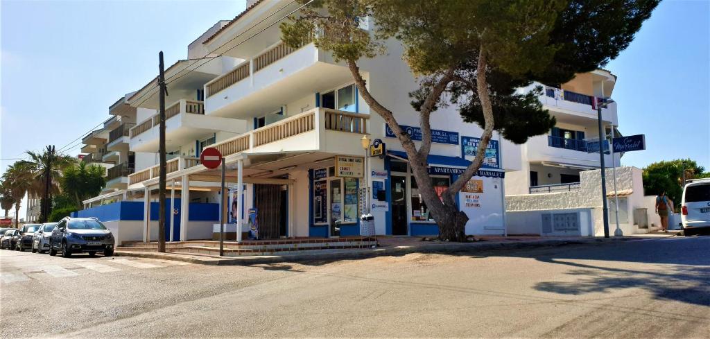 un gran edificio blanco con un coche aparcado delante de él en Apartamentos Can Marsalet en Puerto Colom