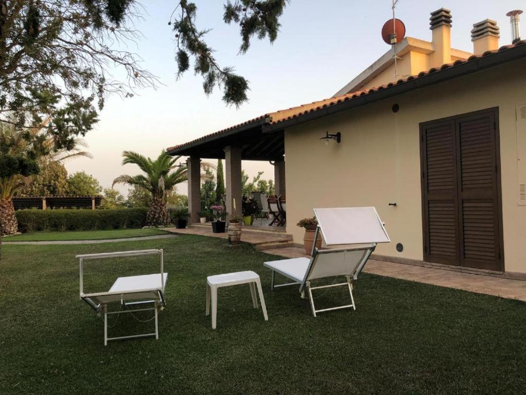 ピティリアーノにあるLa Casa Degli Uliviの家の前の芝生の上に椅子2脚とテーブル