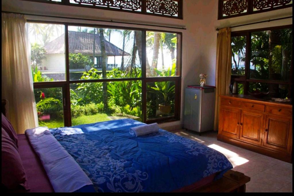 1 dormitorio con cama azul y ventana grande en Jasri Dalem Surf Retreat en Jasri