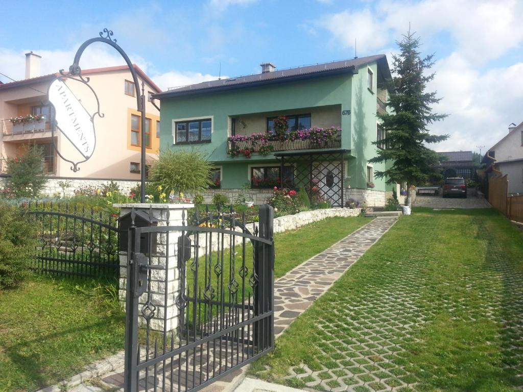 a house with a gate in front of a yard at Apartmány Korenko in Štrba