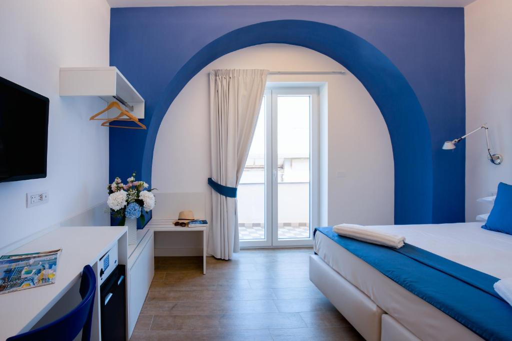 a blue and white bedroom with a bed and a window at Xenia House Sorrento in Sorrento