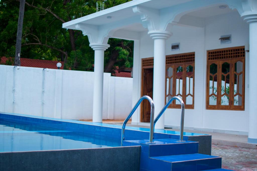 a swimming pool with blue stairs in front of a building at MRD Beach Hotel in Trincomalee