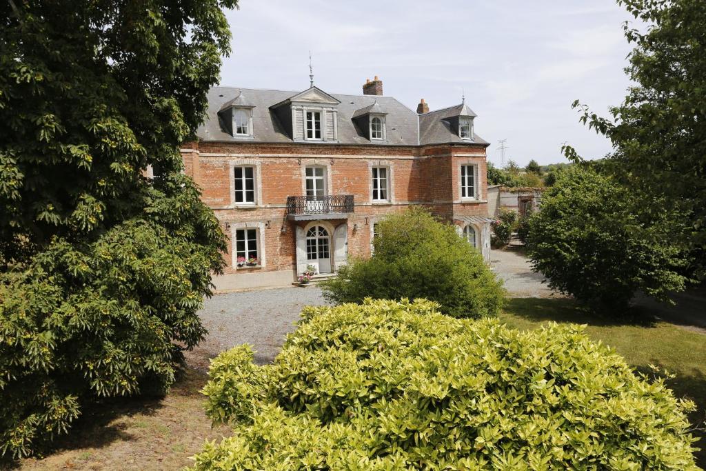 una antigua casa de ladrillo con un balcón en un patio en Au Souffle de Vert en Bouvaincourt-sur-Bresle