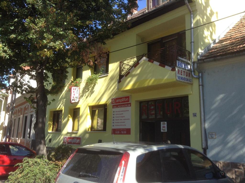 une voiture blanche garée devant un bâtiment jaune dans l'établissement Agria Retur Vendégház, à Eger