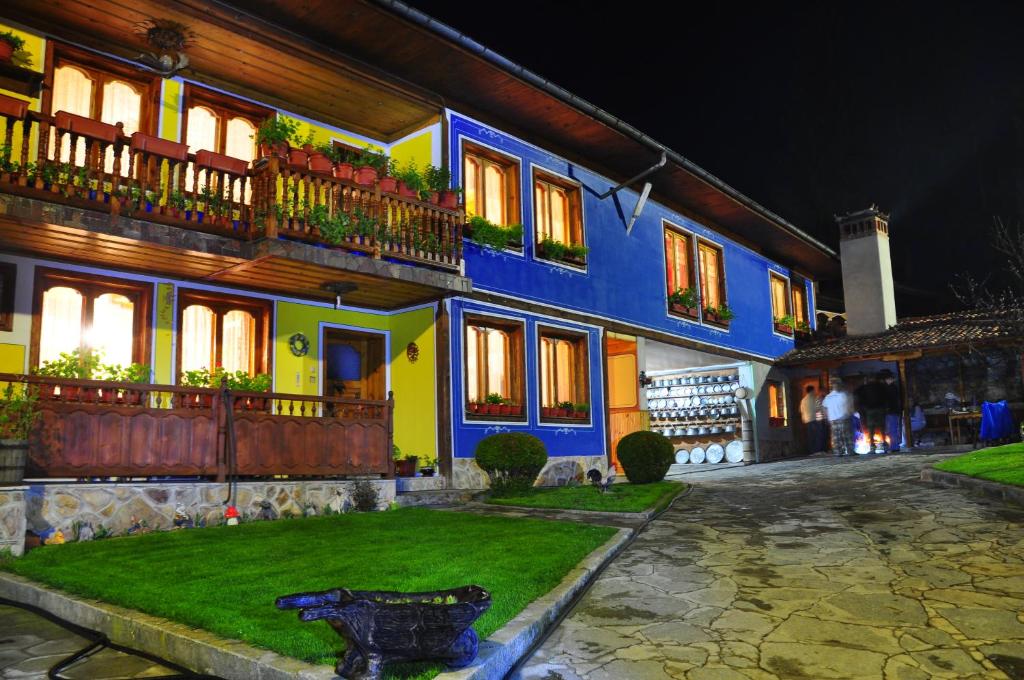 a blue and yellow building with a yard at Hotel Rai in Koprivshtitsa