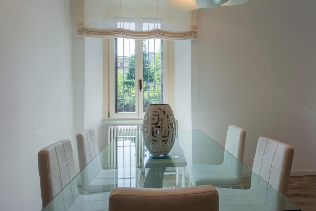 una sala da pranzo con tavolo in vetro e sedie bianche di Apartment old wall Como center a Como