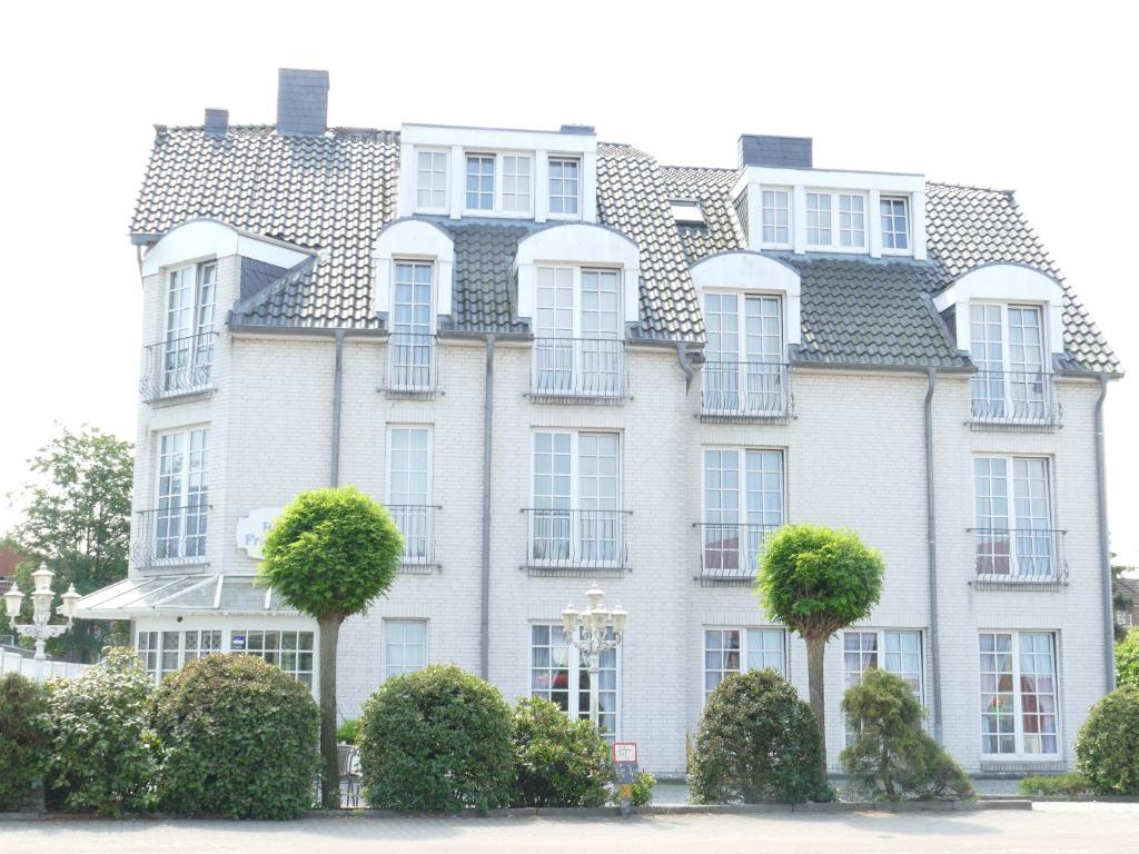 un gran edificio blanco con árboles delante de él en Hotel Friesenhof, en Norderstedt