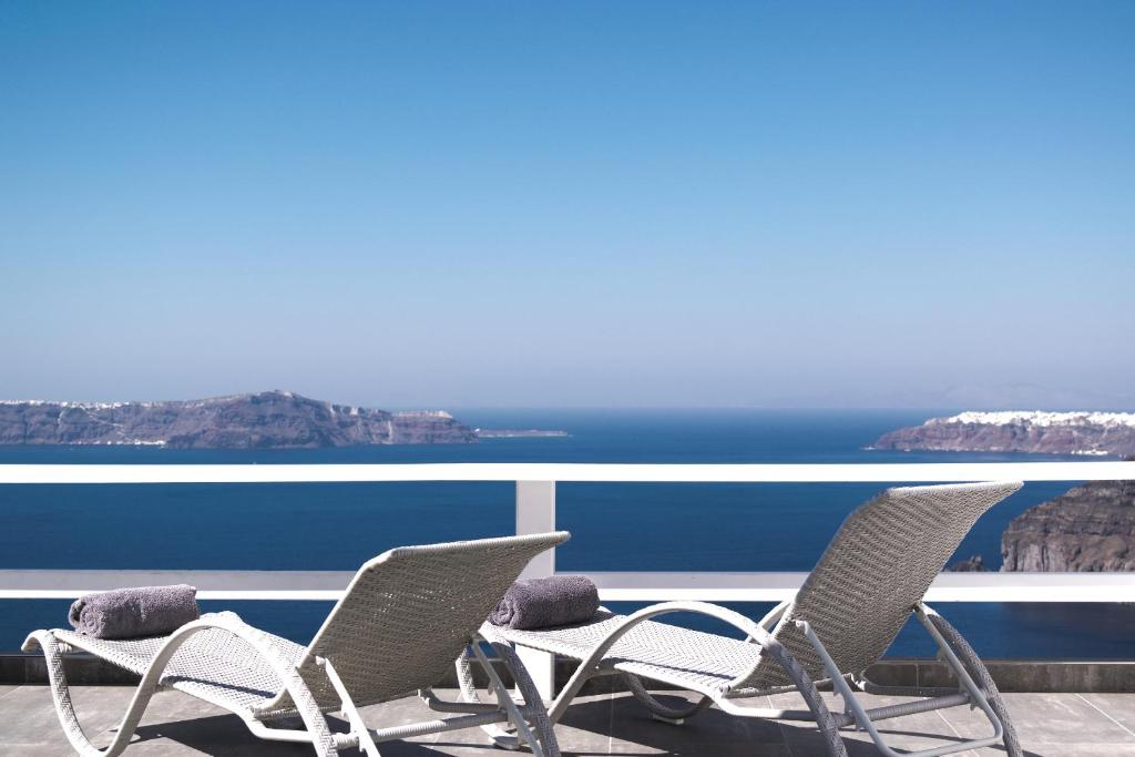 a group of chairs sitting on a balcony overlooking the ocean at Hotel Thireas in Fira