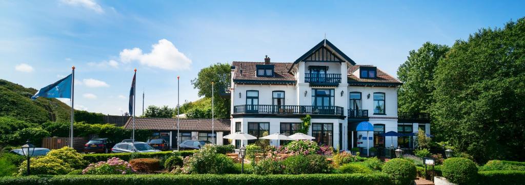 a large white house with a garden in front of it at Boutique hotel Puur Zee - Adults Only in Wijk aan Zee