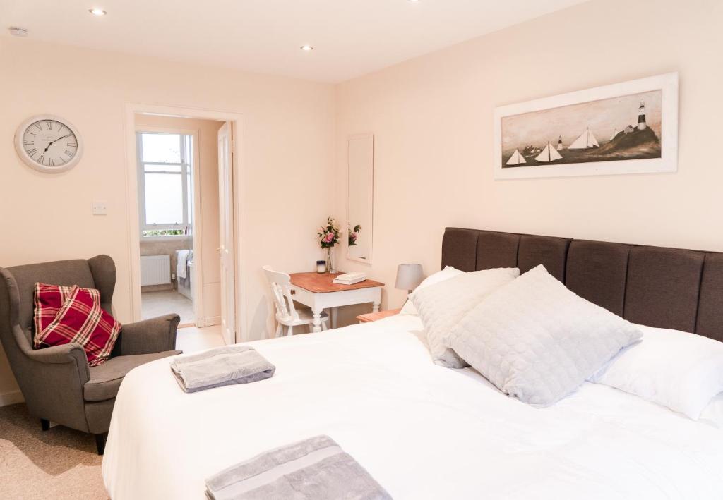 um quarto com uma cama, uma cadeira e um relógio em A Stay On The Brae em Edinburgo