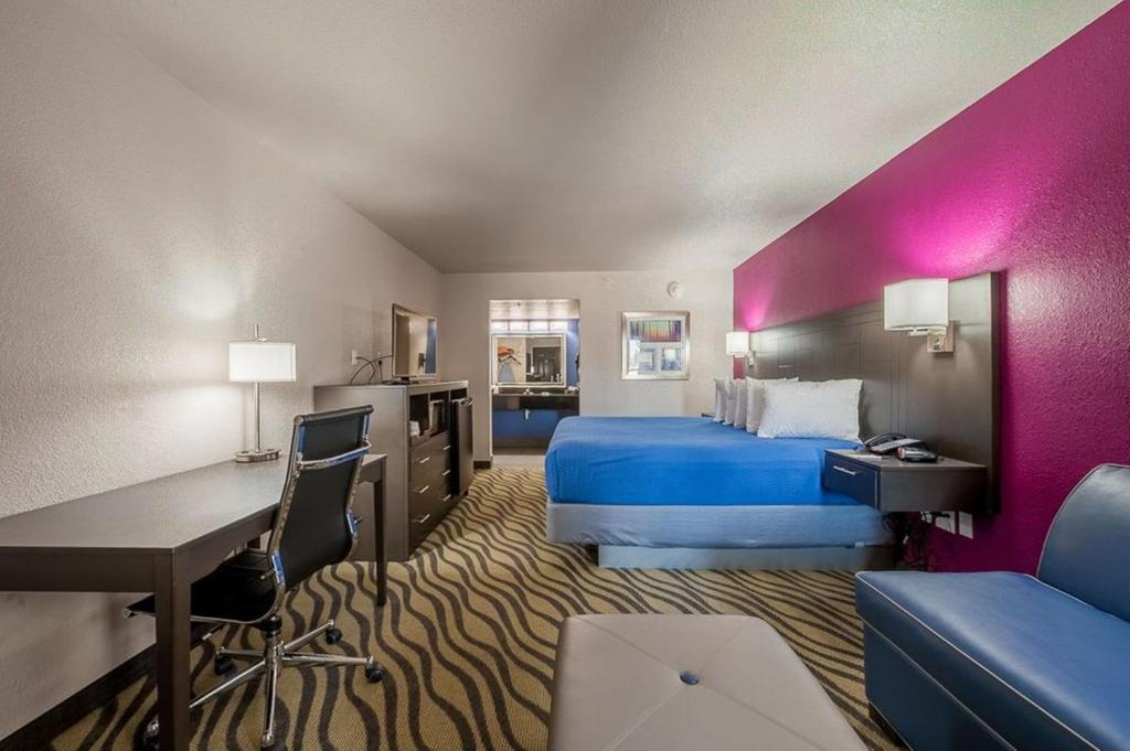 a large hotel room with a bed and a desk at Stratford House Inn in Edmond