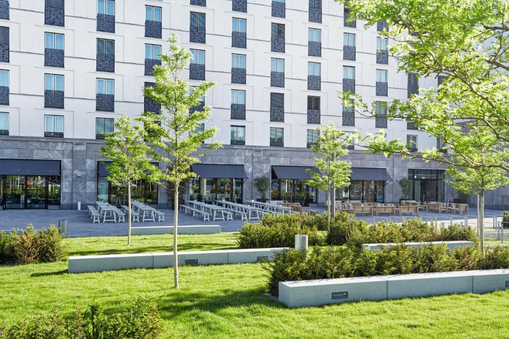an exterior view of a building with trees in a park at H2 Hotel München Olympiapark in Munich