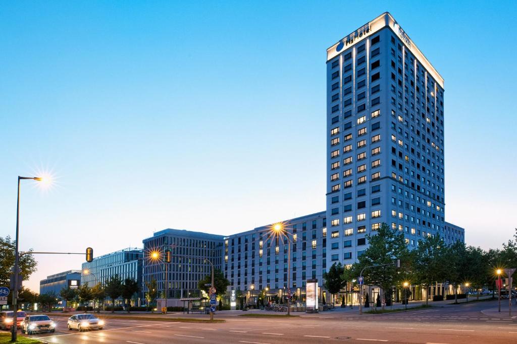 een hoog blauw gebouw met auto's geparkeerd voor het bij H2 Hotel München Olympiapark in München