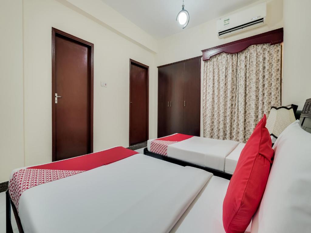 two beds in a hotel room with red pillows at Al Rayan Hotel in Ajman 
