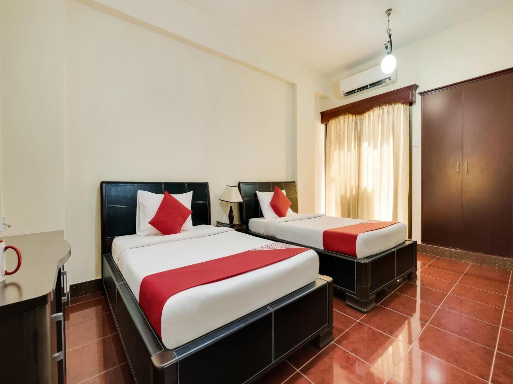 a bedroom with two beds with red pillows at Al Rayan Hotel in Ajman 