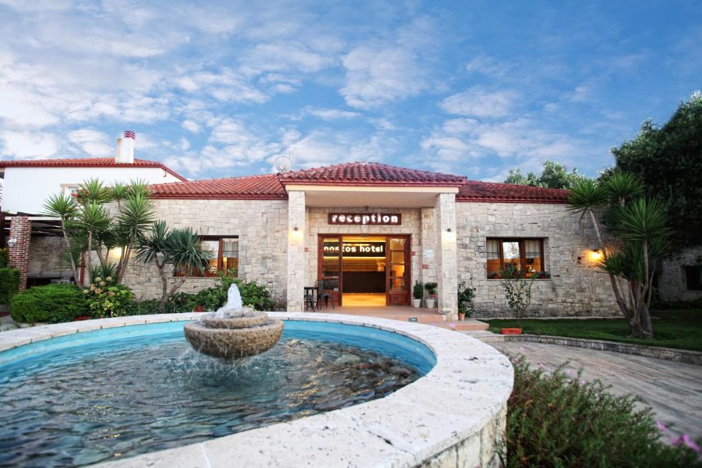a house with a fountain in front of a building at Nostos Hotel in Afitos