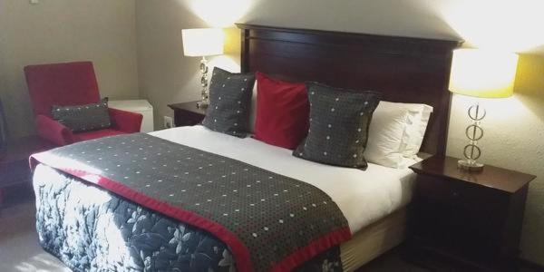 um quarto de hotel com uma cama grande com almofadas em Welkom Inn em Welkom