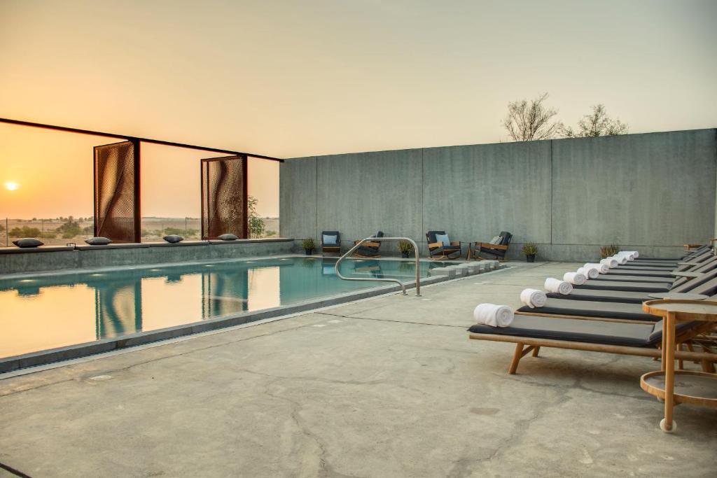 a swimming pool with a row of lounge chairs next to it at Mysk Al Faya Retreat in Sharjah