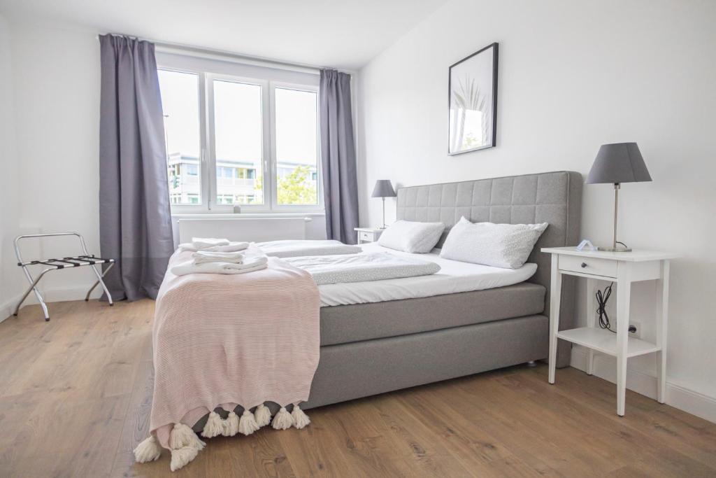 a white bedroom with a bed and a window at Dehnhaide Apartments in Hamburg