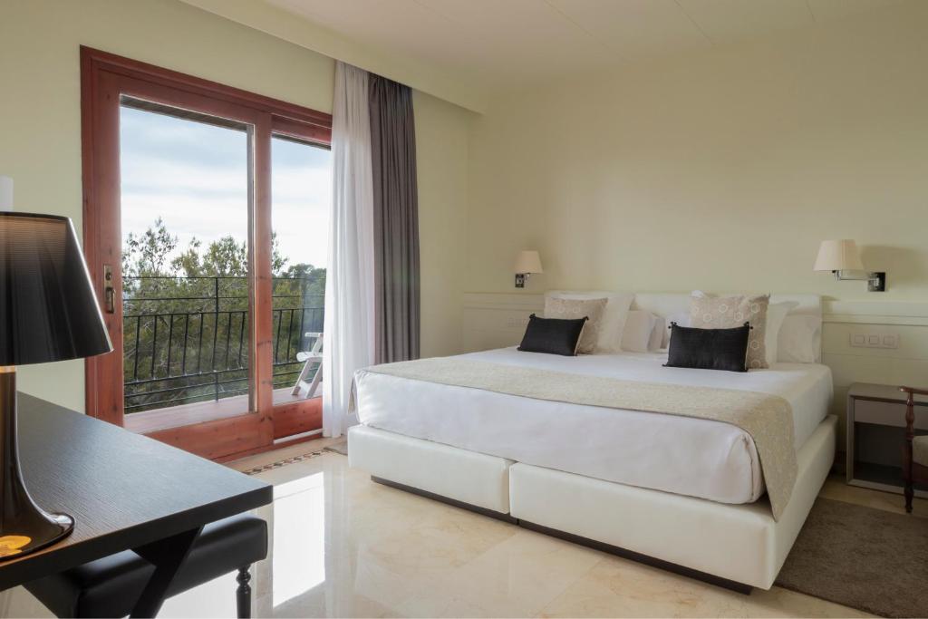 a white bedroom with a large bed and a window at Hotel Santa Marta in Lloret de Mar