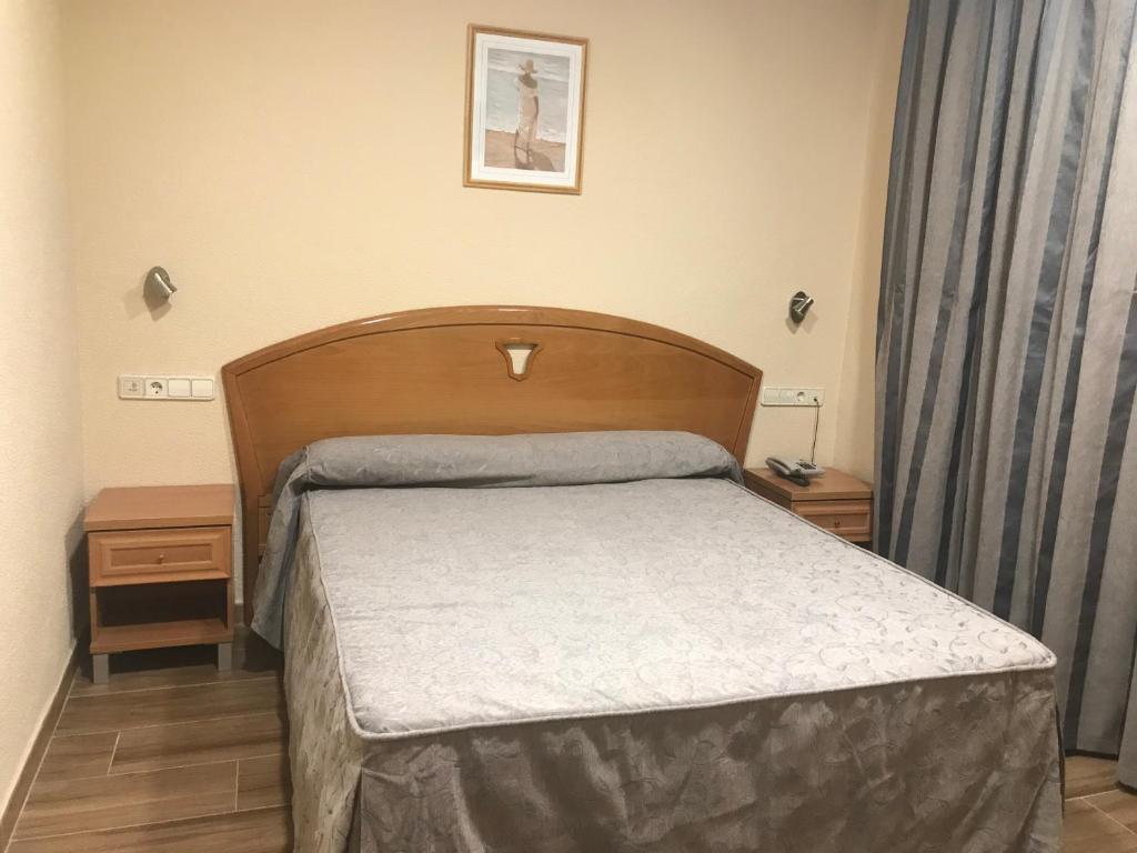 um quarto com uma cama com uma cabeceira de madeira em Hotel La Union em Humanes de Madrid