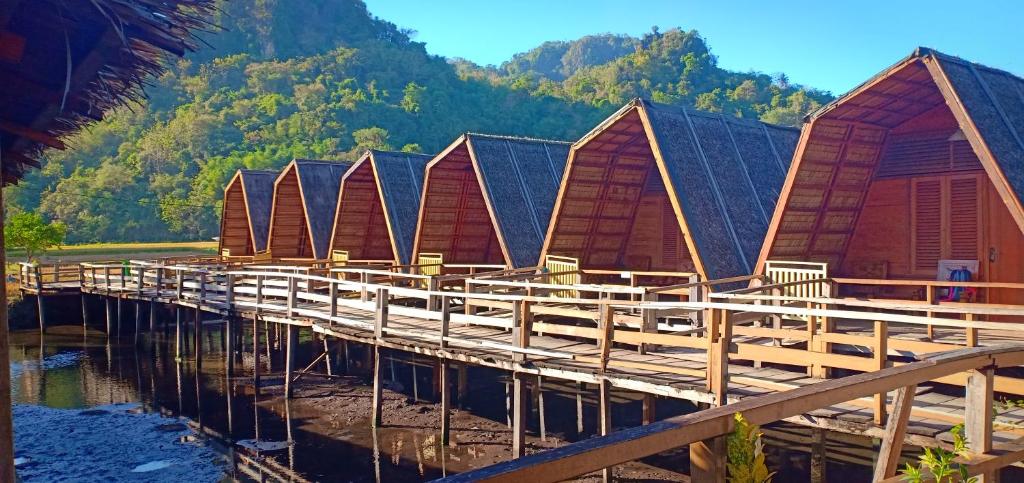 een gebouw met een houtenarf met een berg op de achtergrond bij Rammang Rammang Eco Lodge in Baloci