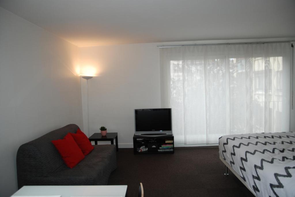 ein Wohnzimmer mit einem Sofa und einem TV in der Unterkunft Appartements Paris Boulogne in Boulogne-Billancourt