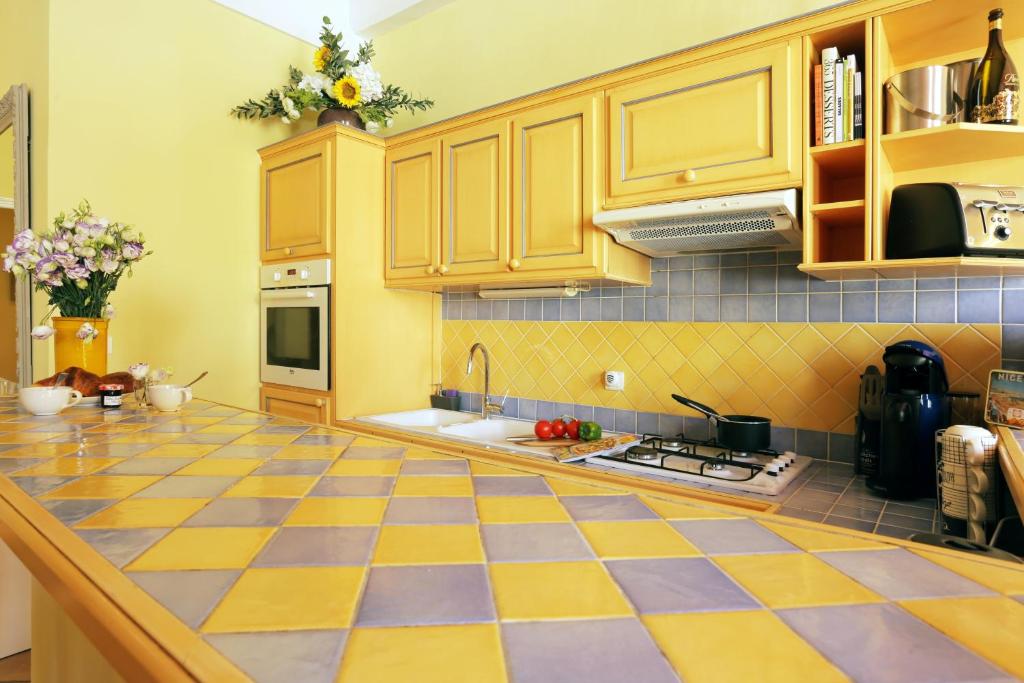 a kitchen with yellow cabinets and a checkered floor at FONTAINE - CHARMING PROVENCAL, Clim, 6 GUEST, OLD TOWN NICE in Nice