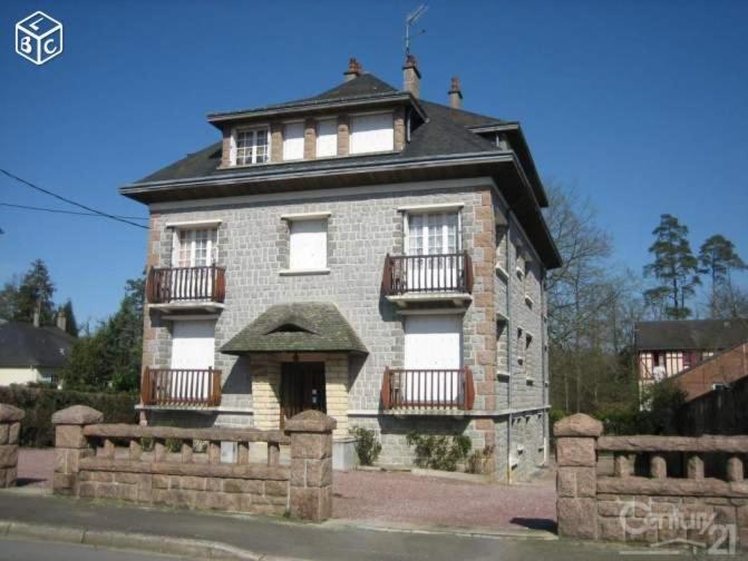 un gran edificio de ladrillo con ventanas y techo en Les cigognes, en Bagnoles de l'Orne