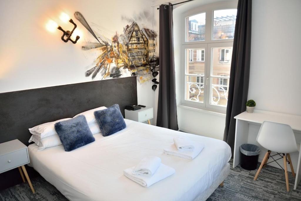 een slaapkamer met een bed met blauwe kussens en een raam bij Hotel des Arts - Centre Cathédrale in Straatsburg