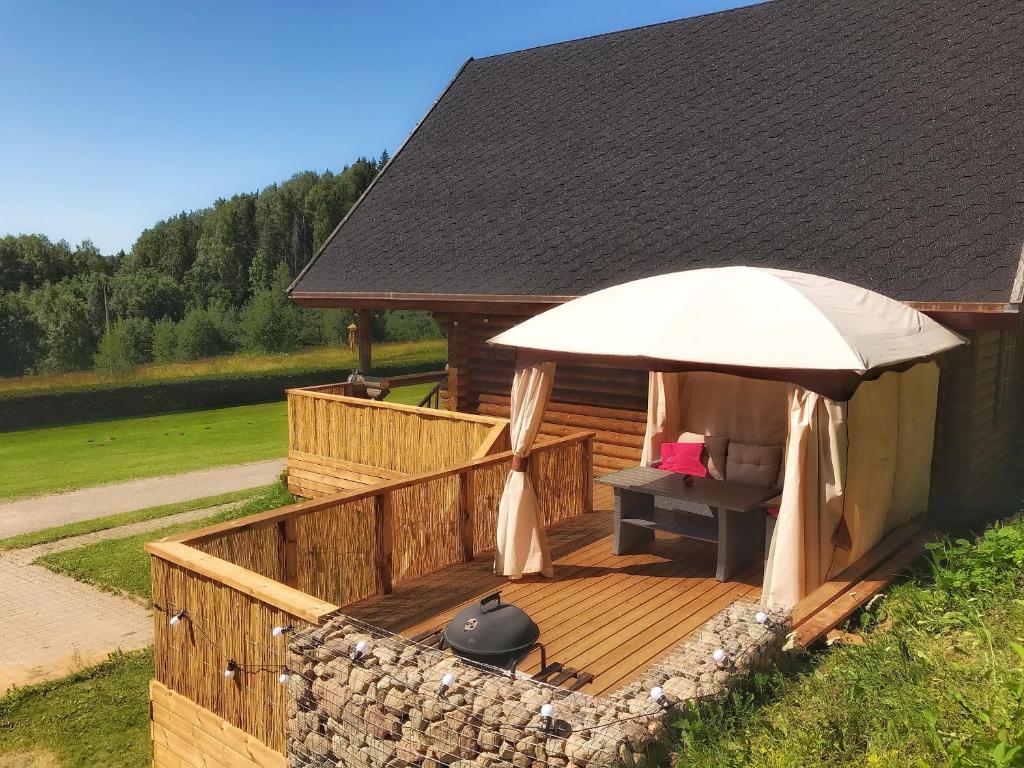 une terrasse en bois avec un parasol et un grill dans l'établissement Kelgumäe, à Otepää