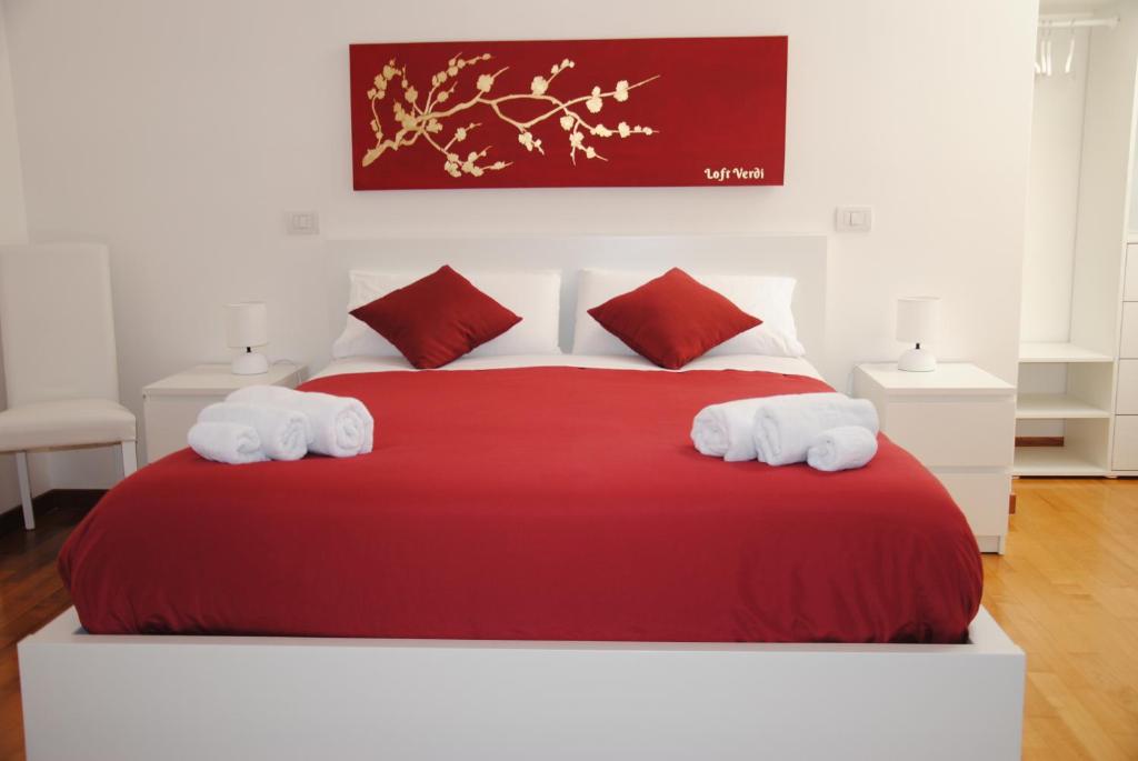un letto rosso con due asciugamani bianchi sopra di Loft VERDI Holiday Viterbo a Viterbo