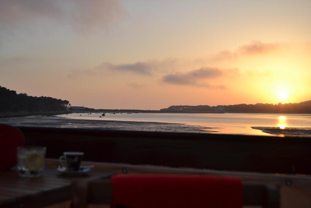 a sunset on the beach with a table and chairs at Apartamento Foz do Rio Minho in Caminha