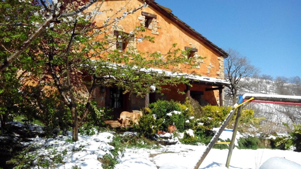 una casa con nieve en el suelo delante de ella en El Escondite del Miera, en San Roque de Ríomiera