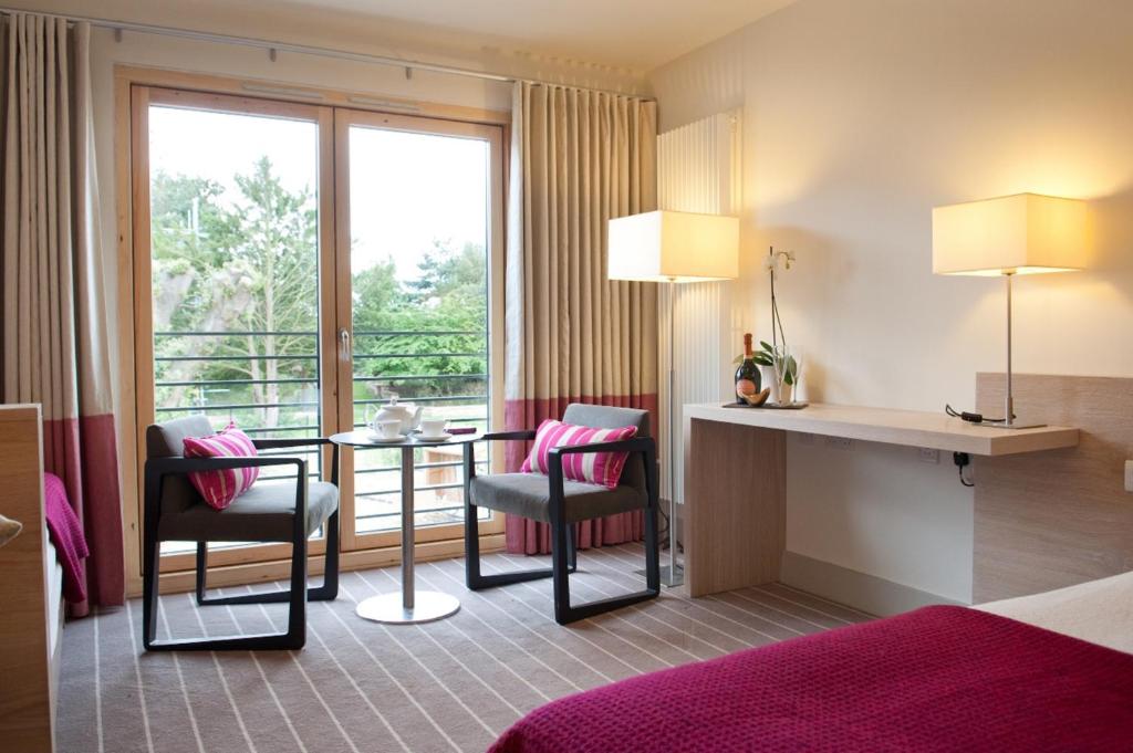 a hotel room with a table and chairs and a window at Lifehouse Spa And Hotel in Frinton-on-Sea