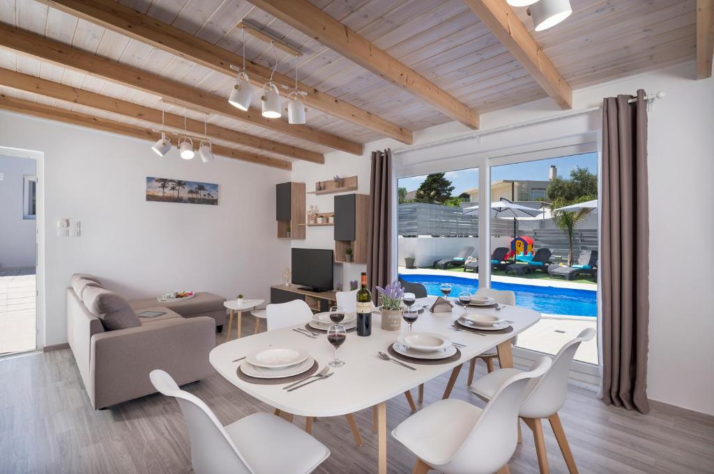 a dining room and living room with a white table and chairs at b&m villas in Metókhion Sirilíou